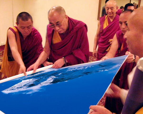 The XIV Dalai Lama unfolds the canvas with the photograph "Ama Dablam The Holy Mountain" by Sergey Melnikoff, a.k.a. MFF